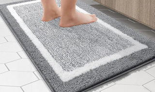 a person standing on a grey and white bathroom rug