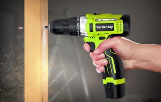 a hand drilling a hole in a piece of wood