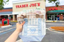 hand holding trader joes mini striped canvas totes outside of store