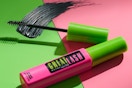 a mascara tube and wand on a pink and green background