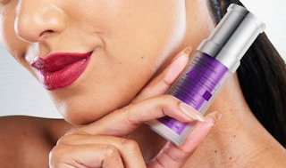 a person holding a purple bottle of face serum