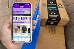 someone looking at amazon haul on their phone next to amazon boxes