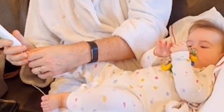 A baby getting nails trimmed by a parent
