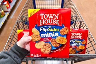 person holding a box of town house flipsides crackers over a cart