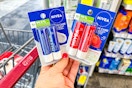 person holding 2 nivea lip balm 2-packs by a cvs cart