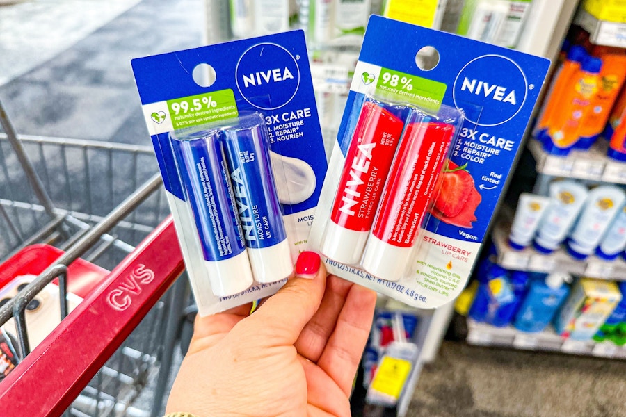 person holding 2 nivea lip balm 2-packs by a cvs cart
