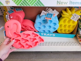 hand holding flamingo ice cube shaped tray with summer shaped ice trays in background