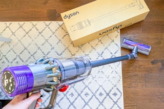 someone using a dyson cordless stick vacuum on their floor
