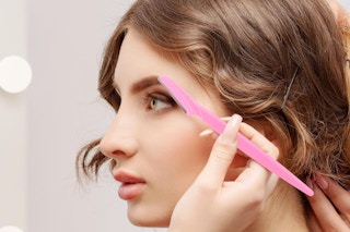 a woman shaving her eyebrows with an eyebrow shavers