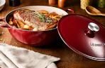 Lifestyle image of a red Le Creuset 5.25-qt Traditional Cast Iron Chef's Oven with food cooked inside 