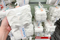 hand holding a pack of carter's bodysuits in front of a target shelf