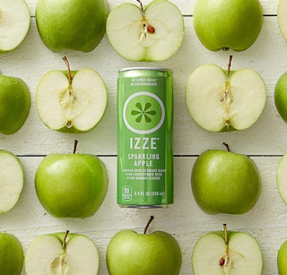 A green can of apple sparkling juice surrounded by green apple halves