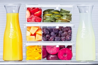 3 Home Edit Bento Boxes stacked on top of each other with food inside (next to two juice containers in fridge)