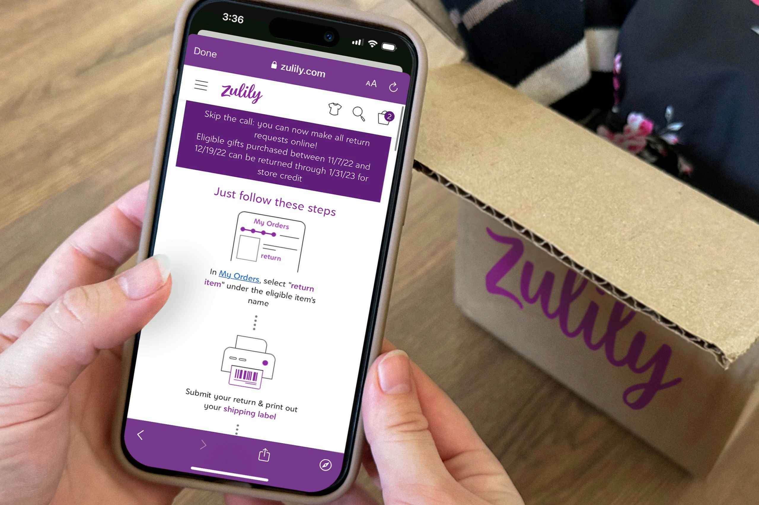 Someone looking up the Zulily return policy on their phone with an open Zulily box in the background