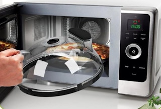 a cover being put over food in a microwave