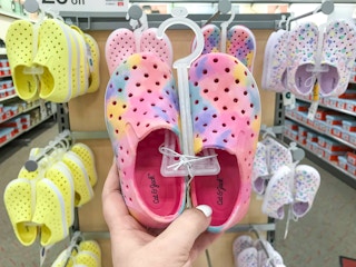 hand holding a pair of toddler water shoes in front of shoe display at Target