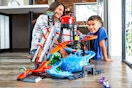 Lifestyle image of the Hot Wheels Ultimate Gator Car Wash Playset played with by a child and mother in home setting (sitting on the floor)