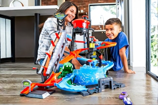 Lifestyle image of the Hot Wheels Ultimate Gator Car Wash Playset played with by a child and mother in home setting (sitting on the floor)