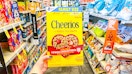 person holding a box of cheerios in an aisle