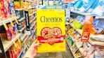 person holding a box of cheerios in an aisle