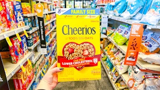 person holding a box of cheerios in an aisle