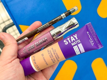 hand holding a Rimmel lip, eye, and face makeup container