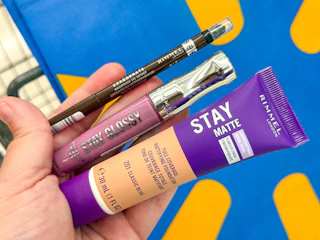 hand holding a Rimmel lip, eye, and face makeup container