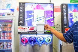 Hand holding a large cup with slurpee machine in the background