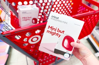 hand holding a cricut easy press mini in front of a target cart