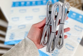 hand holding three iphone lightning charging cables over an amazon package