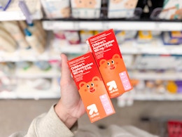 hand holding 2 up & up children's pain reliever in front of target shelf