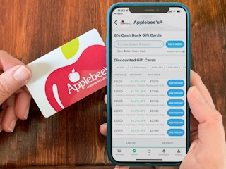 A person holding an Applebee's gift card and cell phone with the raise app open on the screen.