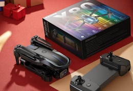 a drone and remote next to it's packaging