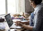 A woman typing on a laptop while sitting at a table.