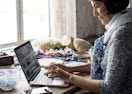A woman typing on a laptop while sitting at a table.