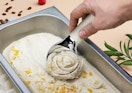 a person using a heated ice cream scooper to scoop ice cream