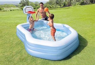 two young boys and an adult male playing basketball in inflatable swimming pool