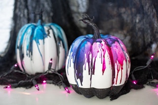 Two artificial craft pumpkins with colored crayons melted down the sides.