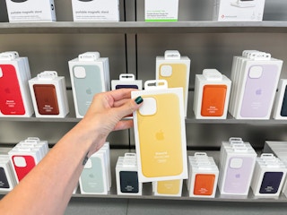 An iPhone case held out in front of a shelf full of other iPhone cases.
