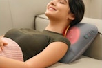 Woman laying on a couch using the SKG Cordless Back Massager.