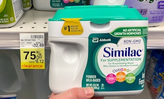 A person's hand holding a container of Similac next to a sale tag for 75% off in CVS.