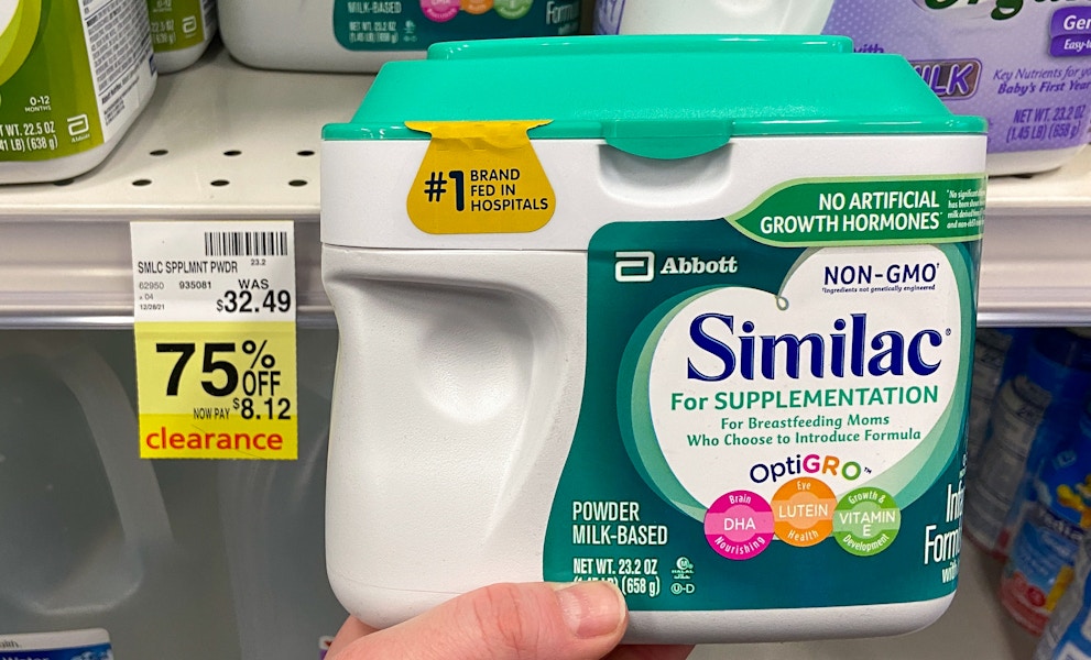 A person's hand holding a container of Similac next to a sale tag for 75% off in CVS.