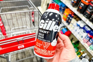 person holding a can of gillette shave foam over a cvs cart