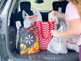 a person unloading a back of the car full of grocery bags