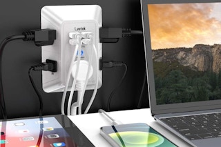 a phone, tablet and laptop plugged into a wall surge protector