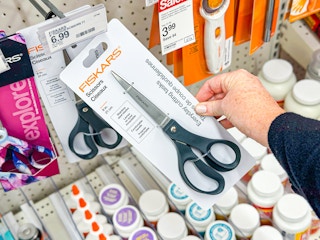 hand holding fiskars scissors next to sale sign at target