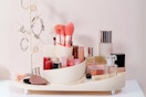An oval cream makeup vanity bathroom countertop tray with a round rotating holder in the middle and a jewelry tree on one side.
