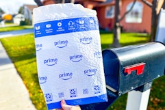 a hand holding an envelope in front of a mail box