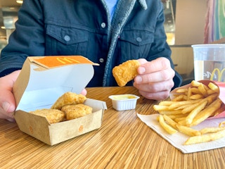 someone sitting in mcdonalds with six-piece chicken mcnuggets, honey mustard, and fries