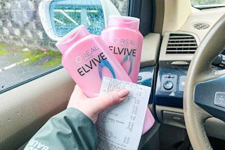 hand holding l'oreal elvive shampoo and a receipt in a car